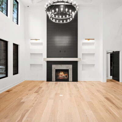 A touch of contemporary with wood flooring, shelved fireplace, modern staircase with multiple windows overlooking the backyard